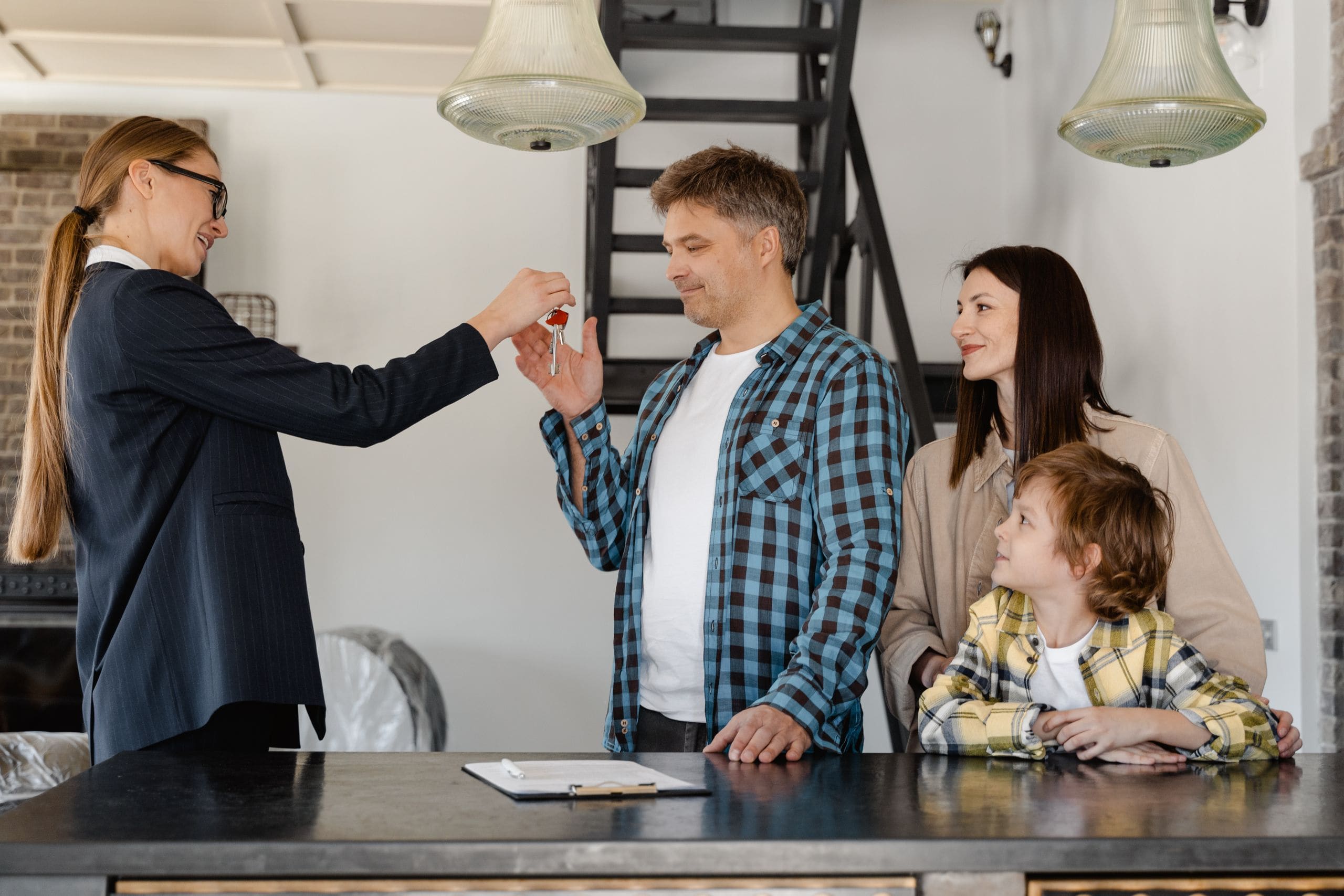 An advisor handing keys to a smiling young couple in front of a newly completed multiplex