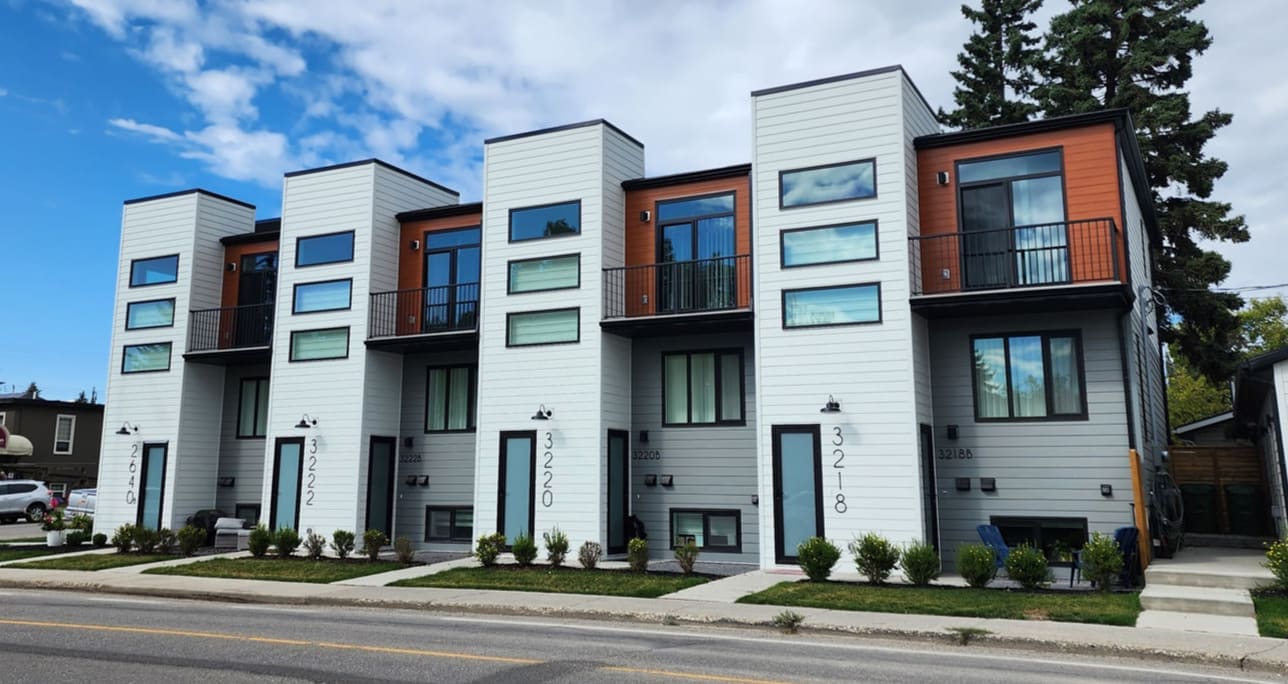 Modern 8-plex row of townhomes with white and orange siding in Calgary
