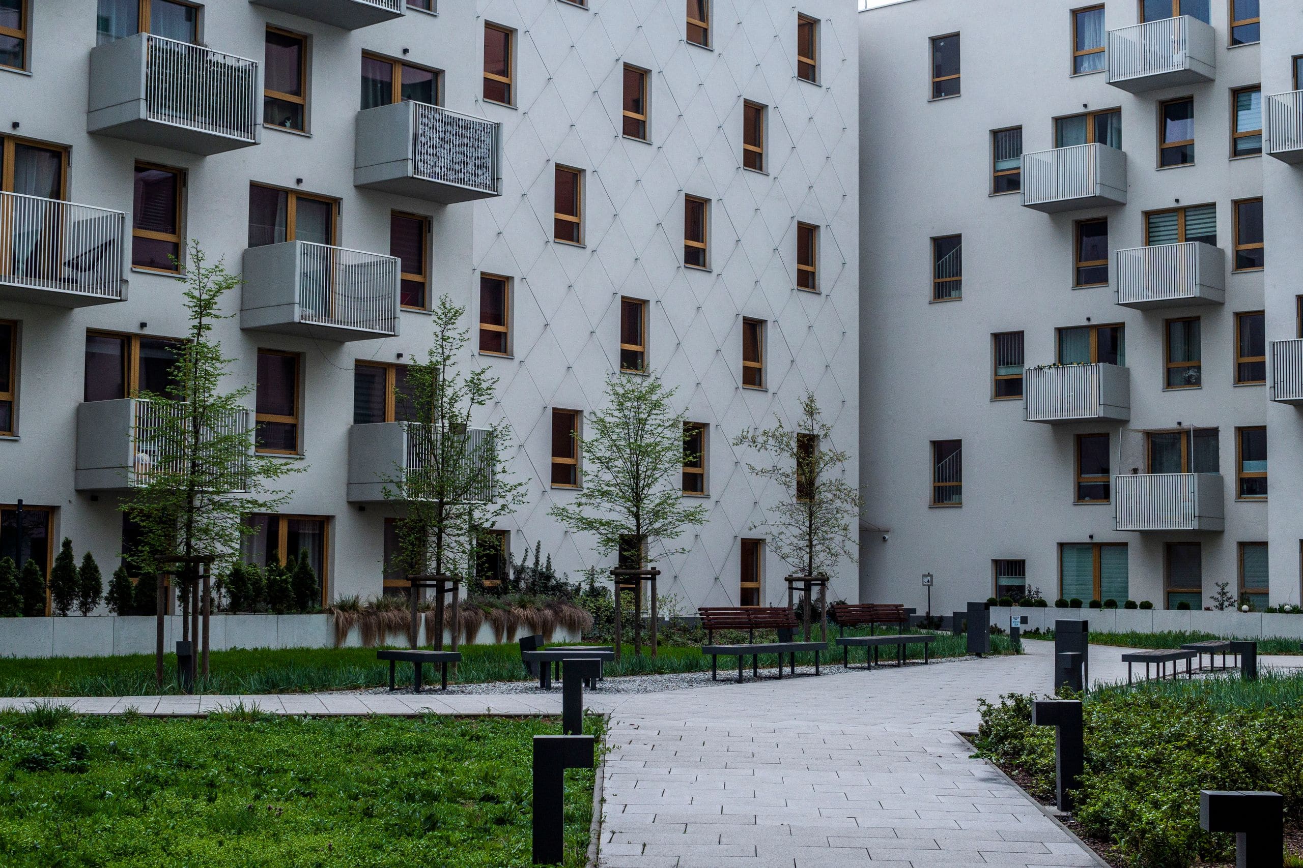 Contemporary apartment buildings along a landscaped pedestrian walkway at sunrise
